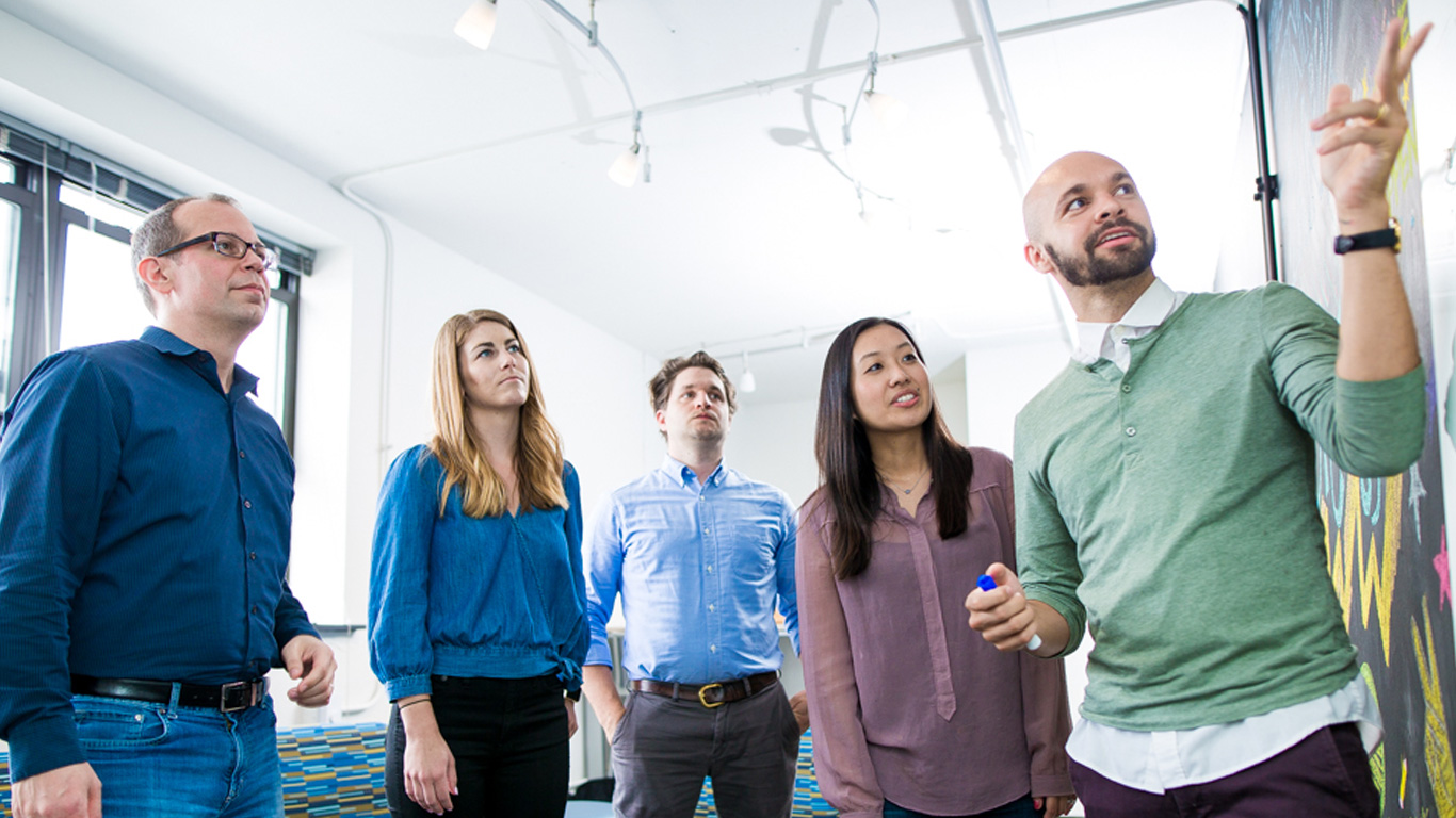 Bounteous employees collaborating around a white board