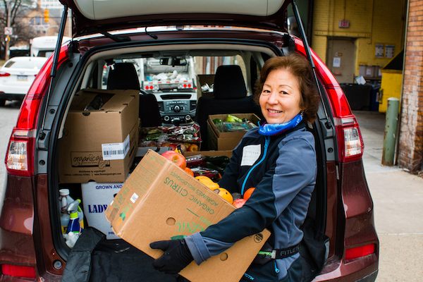 woman loading a box of food into a vehicle