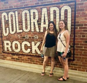 two girls pose at the Rockies game outside of the stadium 