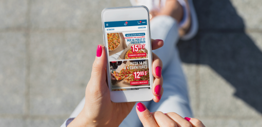 Women walking holding her phone in her hands which is displaying the Domino's Canada app