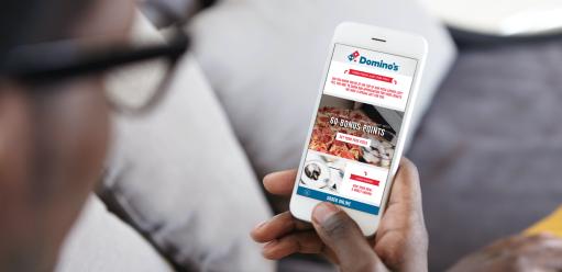 Man holding phone staring at the Domino's app on his screen