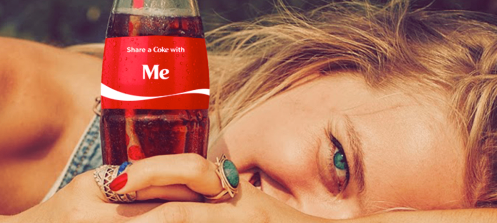 Smiling woman laying sideways holding a bottle of coke that says me